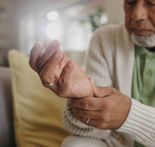 A man holding his wrist to try to alleviate the pain associated with arthritis.