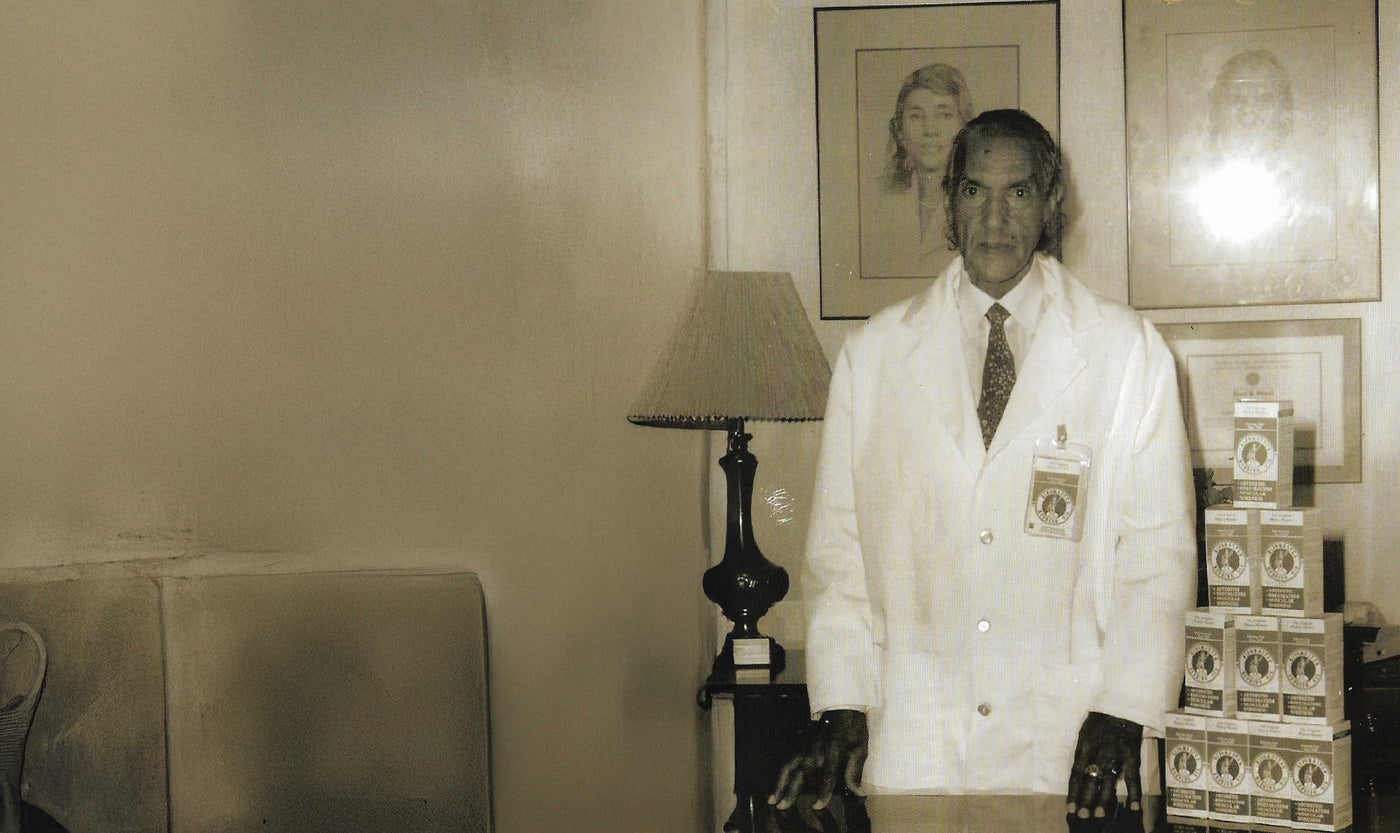 Frank Sewell in a lab coat standing next to stacked boxes of Ringmaster Rubbing Oil.